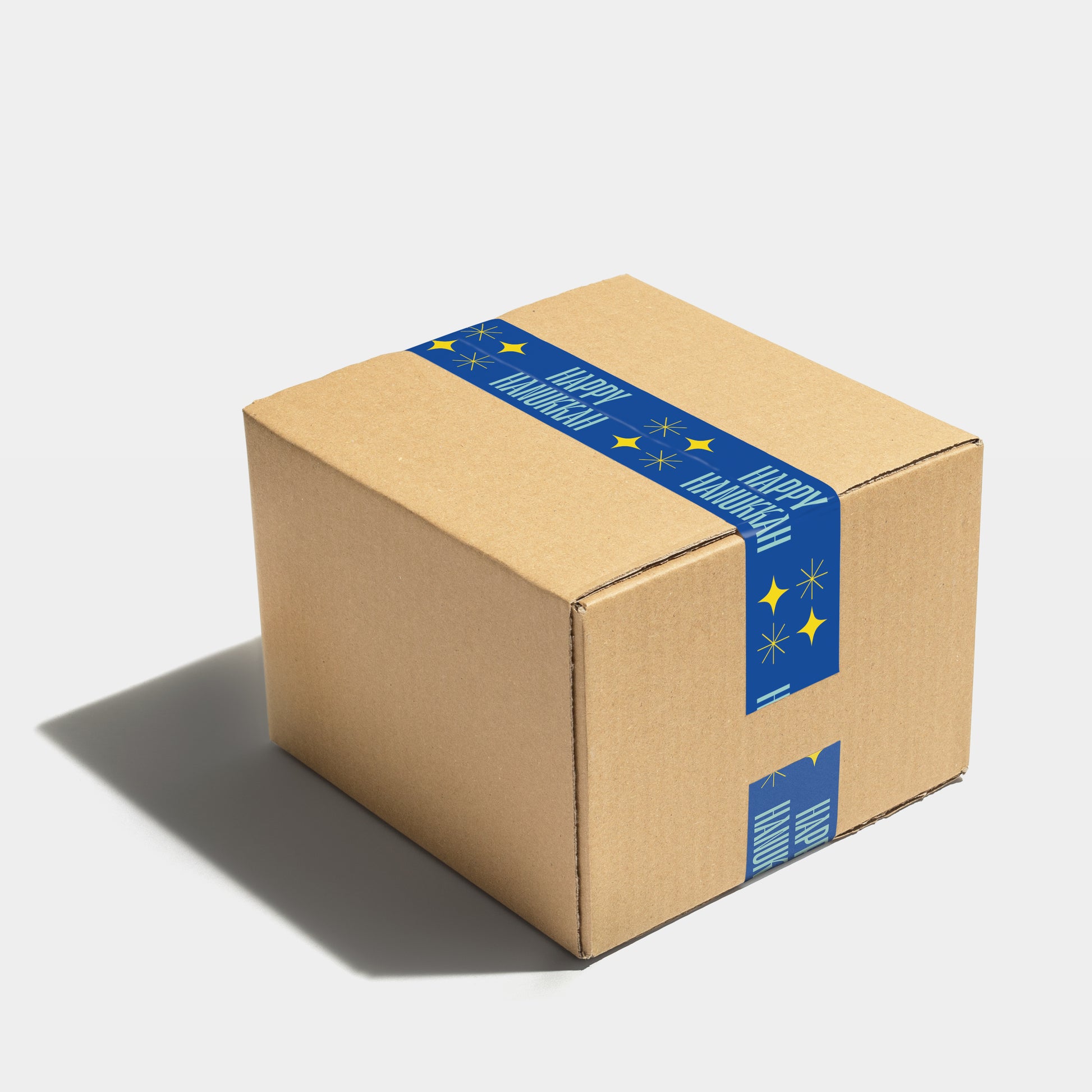 Blue and yellow 'Happy Hanukkah' festive shipping tape on a securely sealed box.