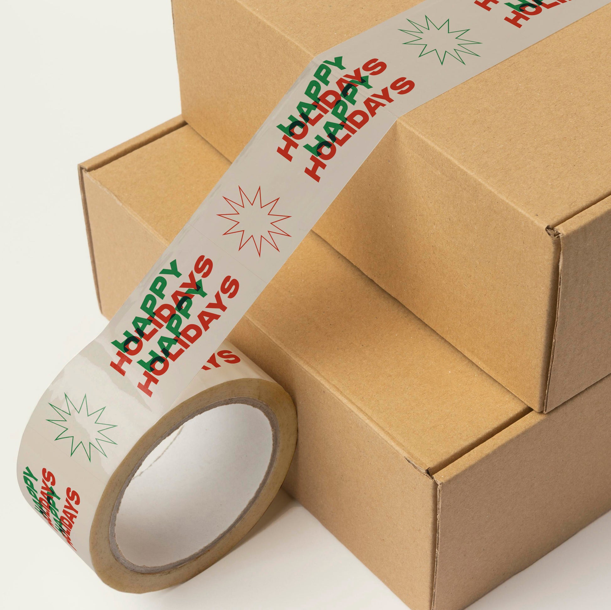 A stack of Christmas gift boxes taped with colorful printed shipping tape with wavy text that reads "happy holidays".