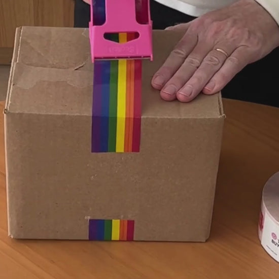 A person shows support for the LGBTQ+ community by taping a box with rainbow pride flag craft tape.