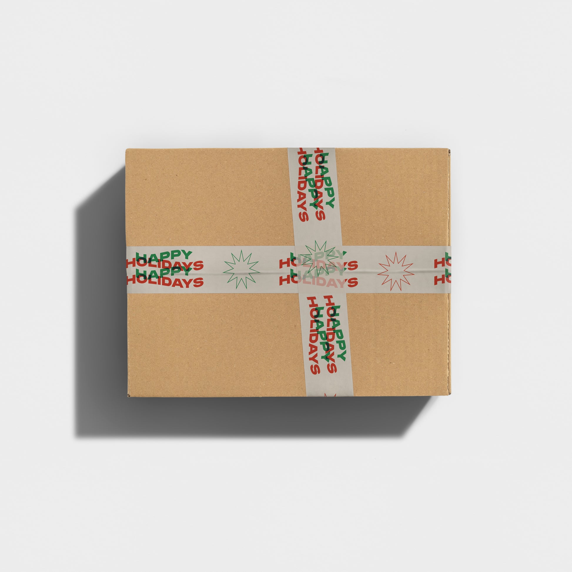 A small gift box taped with colorful printed shipping tape with wavy text in bold font that reads "happy holidays".